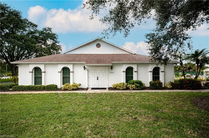 View of front of property with a front yard, stucco siding, and a shingled roof