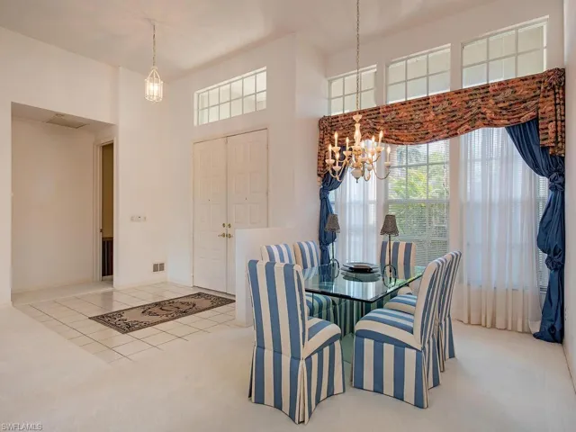 Tiled dining room with a chandelier and a high ceiling