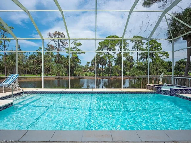 View of pool featuring an in ground hot tub, a water view, and glass enclosure