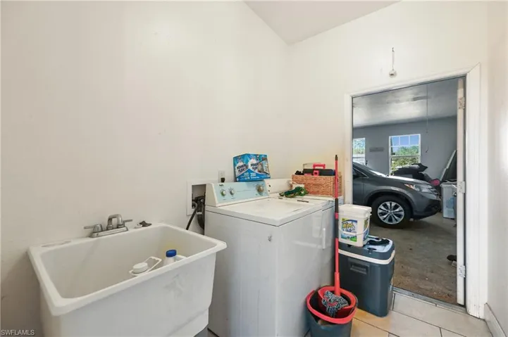 Washroom with washer / clothes dryer and light tile patterned flooring