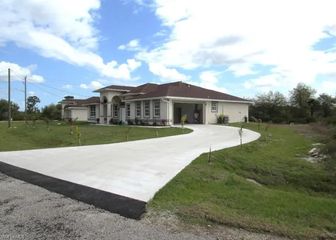 View of front of home featuring a front yard, driveway, and stucco siding