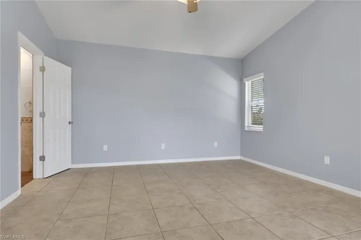 Spacious interior room featuring tile flooring, light blue walls, and a white paneled door