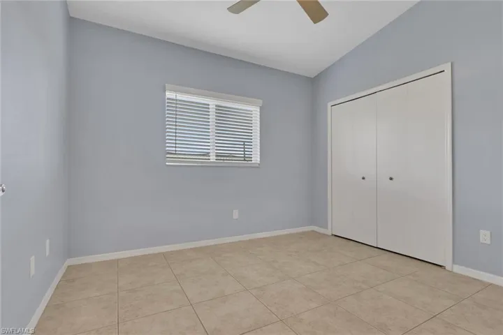 Room featuring tile flooring, neutral wall tones, a window with blinds, and a built-in closet with bifold doors