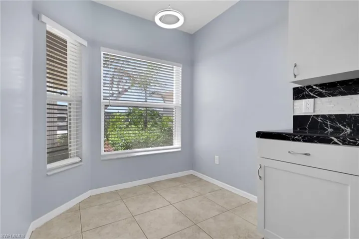 Breakfast nook featuring two large windows with blinds, ceramic tile flooring, and a modern ceiling fixture