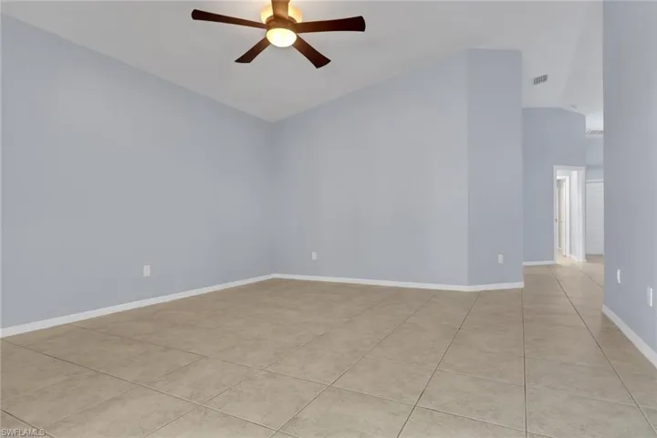 Spacious interior room featuring vaulted ceilings and a ceiling fan with integrated lighting