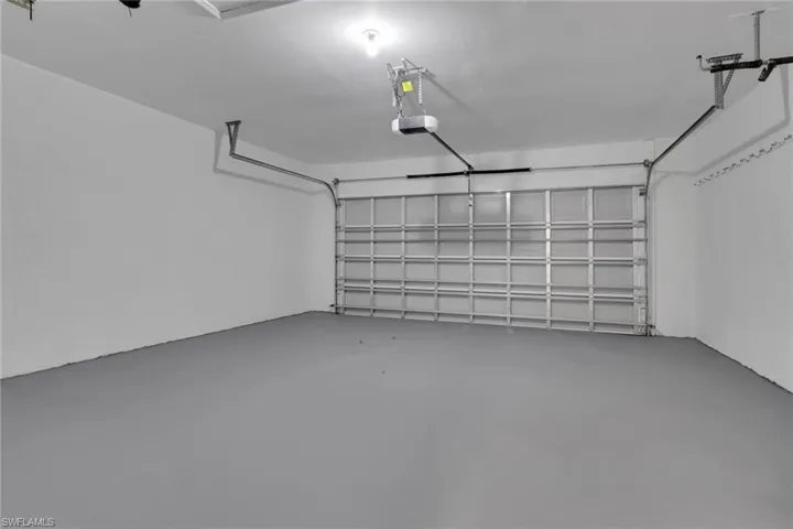 Spacious garage featuring a durable gray epoxy floor, white painted walls, and an automatic garage door opener