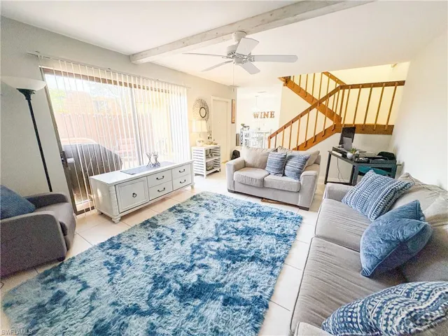Tiled living room featuring ceiling fan and beamed ceiling