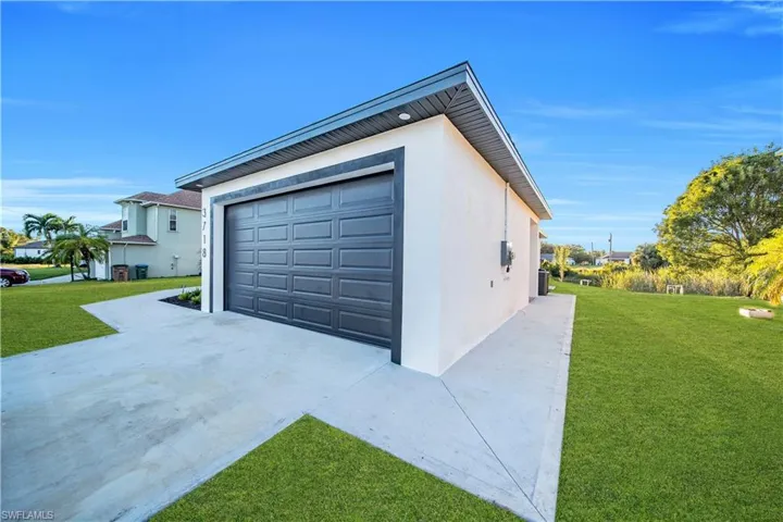 Detached garage featuring smooth stucco siding, a panelized sectional door, and concrete driveway