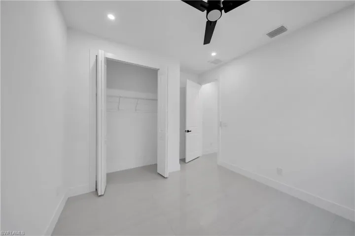 Room featuring light-toned tile flooring, recessed lighting, a matte black ceiling fan, and a built-in closet with bifold doors
