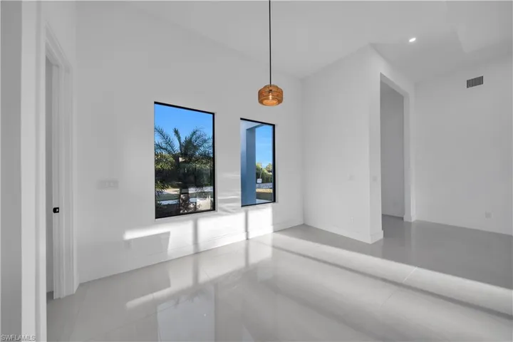 High ceilings featuring a minimalist pendant light, large-format tile flooring, and oversized vertical windows