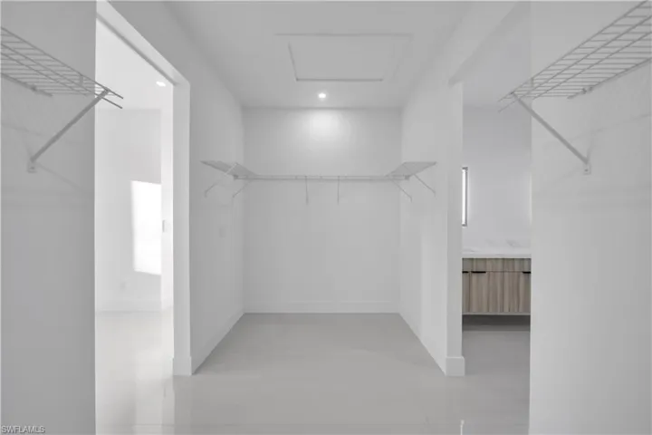 Walk-in closet featuring white walls, large-format tile flooring, recessed ceiling lighting, and wire shelving