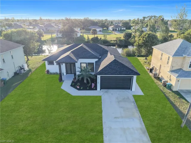 Single-story residence featuring a hipped roof, attached garage, concrete driveway, and waterfront positioning
