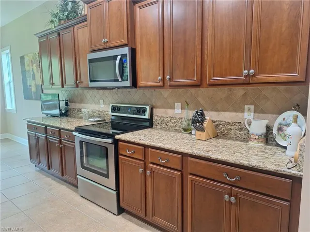 Kitchen with stainless steel appliances, light tile patterned floors, and decorative backsplash