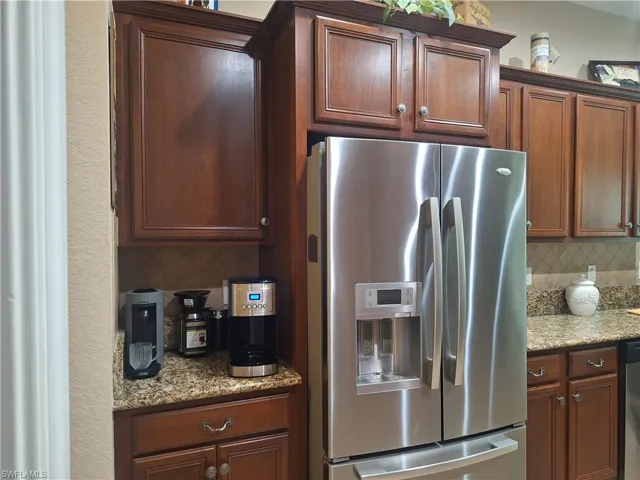 Kitchen with appliances with stainless steel finishes, tasteful backsplash, and light stone counters