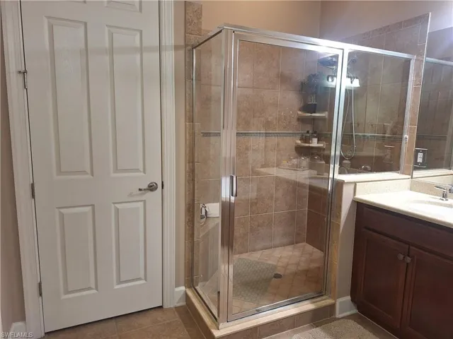 Full bath with vanity, a shower stall, and tile patterned floors