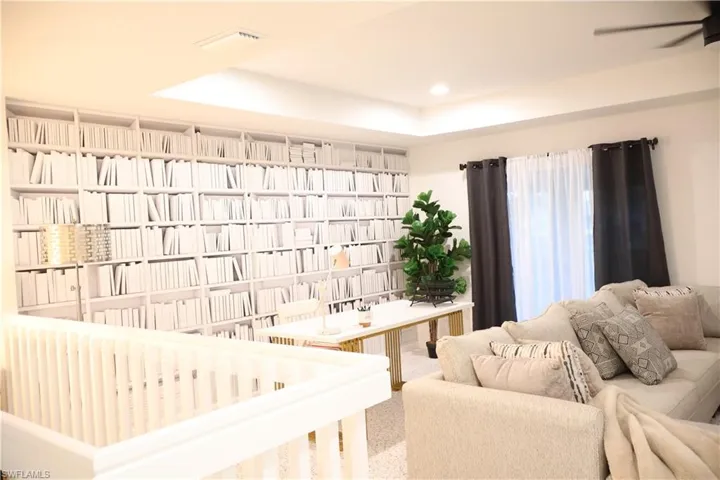 Living room featuring a raised ceiling, ceiling fan, and recessed lighting