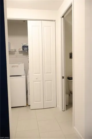 Laundry area with independent washer and dryer and light tile patterned floors