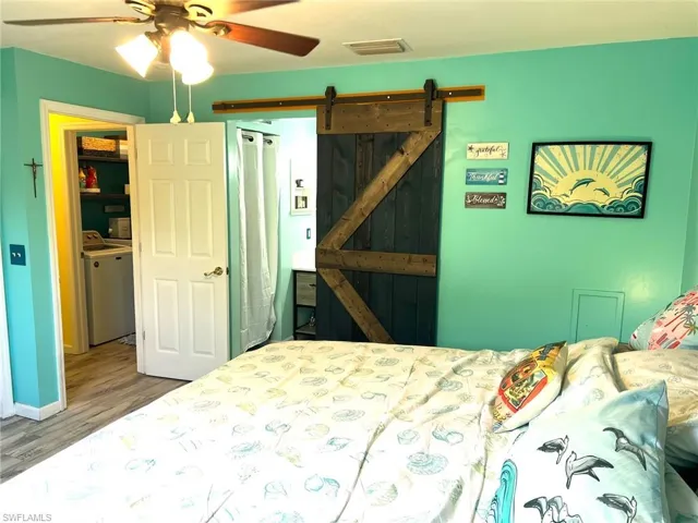 Master Bedroom with  a barn door, new tile wood-style flooring, and ceiling fan