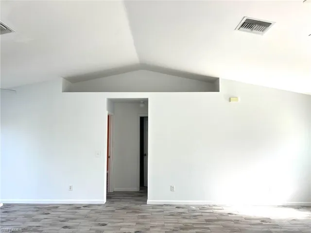 Unfurnished room with lofted ceiling and light hardwood / wood-style flooring
