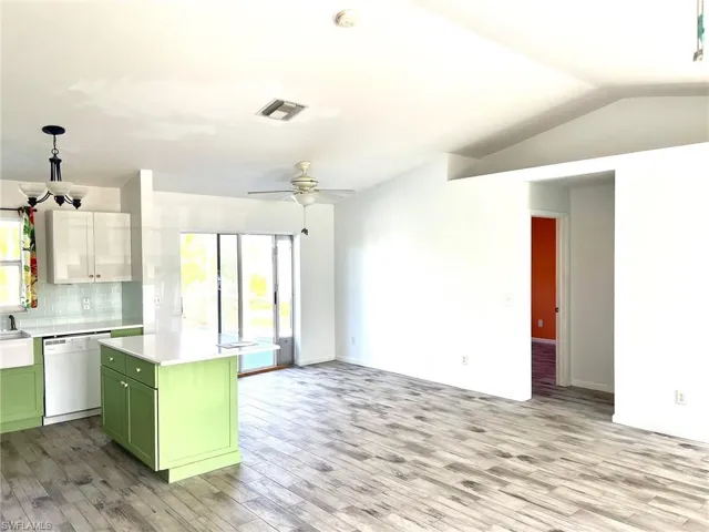 Kitchen with dishwasher, a center island, backsplash, green cabinetry, and ceiling fan