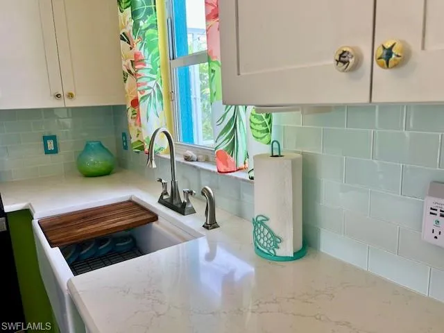 Kitchen with sink, white cabinets, and tasteful backsplash