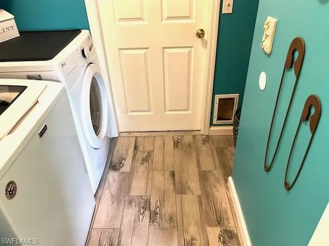Laundry area with washer and dryer and wood-type flooring