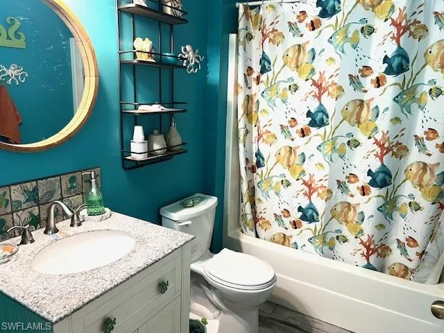 Second bathroom featuring vanity, shower / bath combination with curtain, and toilet