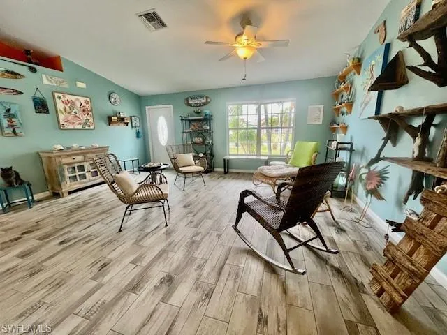Living area with lofted ceiling, light hardwood / wood-style floors, and ceiling fan