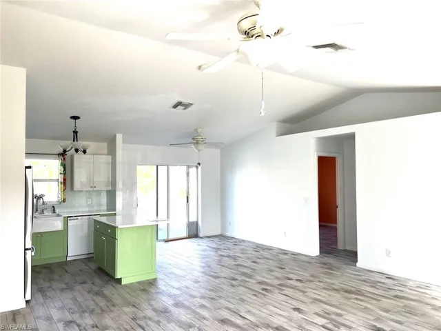 Kitchen with ceiling fan, white dishwasher, decorative backsplash, a kitchen island, and green cabinetry