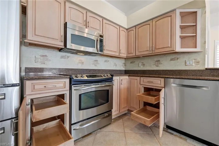 Kitchen with granite  countertops, appliances with stainless steel finishes, light tile floors, and wood cabinets