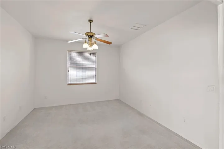 Carpeted Den with ceiling fan and large window.