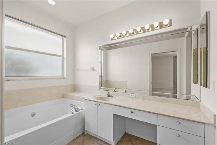 Primary Bathroom featuring vanity, tile floors, and a bathing tub