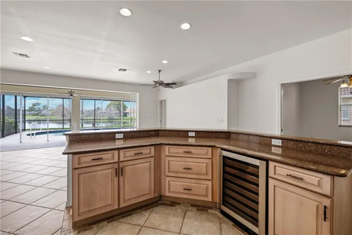 Kitchen with wine cooler, light tile flooring, granite countertops, and ceiling fan