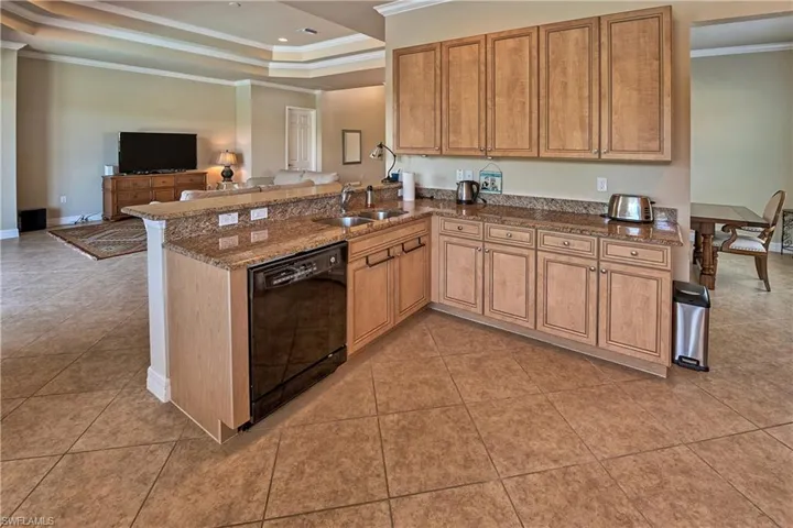 Kitchen featuring black dishwasher, sink, kitchen peninsula, crown molding, and a tray ceiling