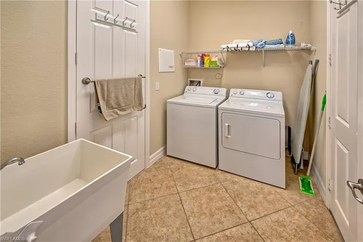 Laundry room with sink, washer and clothes dryer, and light tile patterned floors