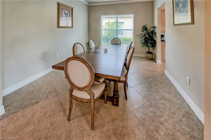 Dining area with light tile patterned flooring and ornamental molding