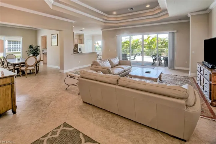 Tiled living room with crown molding and a tray ceiling