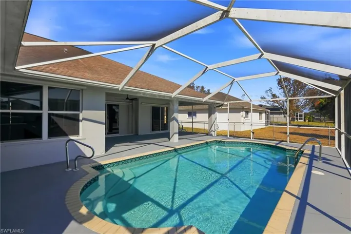Outdoor pool with a sunroom, a patio area, and glass enclosure