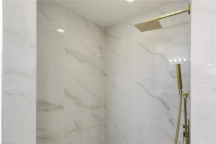 Full bath with a marble finish shower
