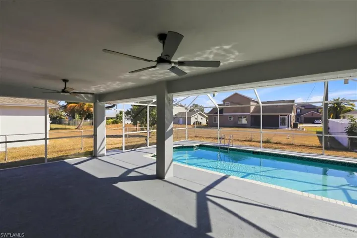 Swimming pool featuring a patio, a sunroom, a residential view, and glass enclosure