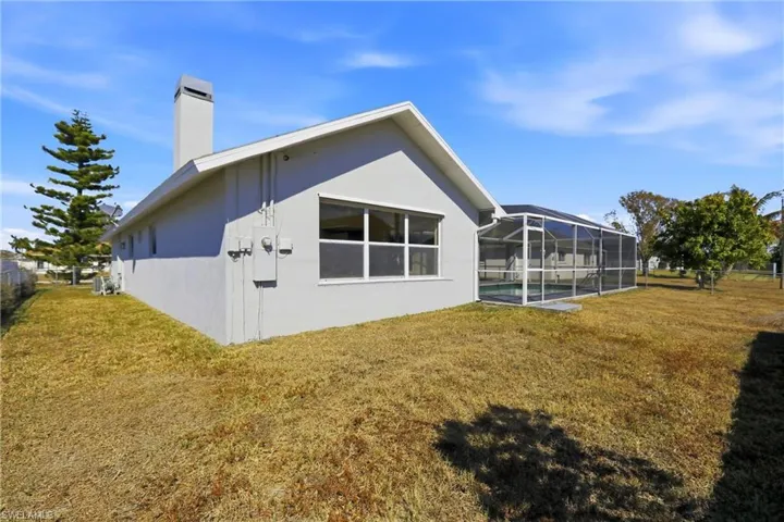 View of home's exterior with a sunroom, a lanai, a chimney, stucco siding, and a pool