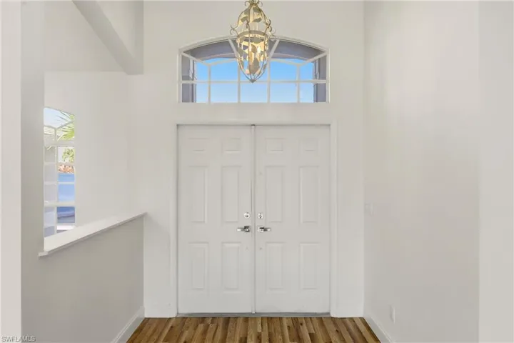 Foyer entrance with plenty of natural light, wood finished floors, a chandelier, and a high ceiling