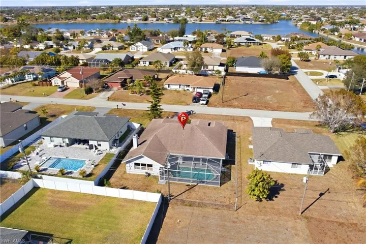 Aerial view of residential area featuring a pool area and a nearby body of water