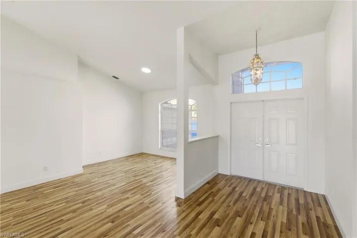 Foyer entrance with lofted ceiling, dark wood finished floors, and suspended lighting