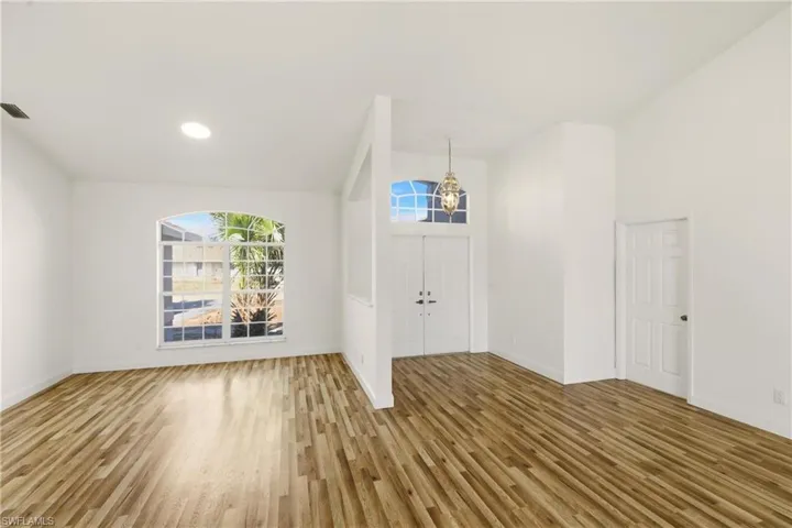 Foyer with light wood finished floors, suspended lighting, and vaulted ceiling