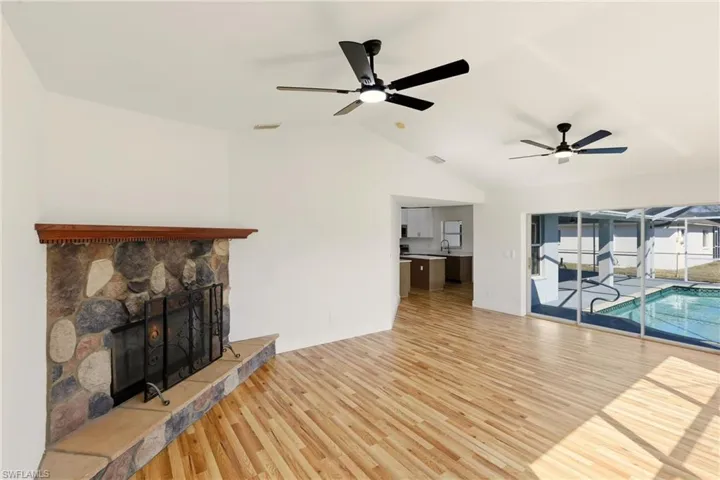 Unfurnished living room with ceiling fan, light wood-style floors, lofted ceiling, and a fireplace