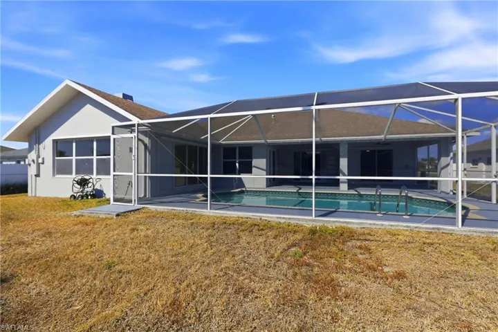 Back of house with a sunroom, an outdoor pool, glass enclosure, stucco siding, and a yard