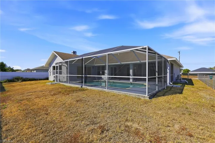 Back of property with a fenced backyard, glass enclosure, and a sunroom