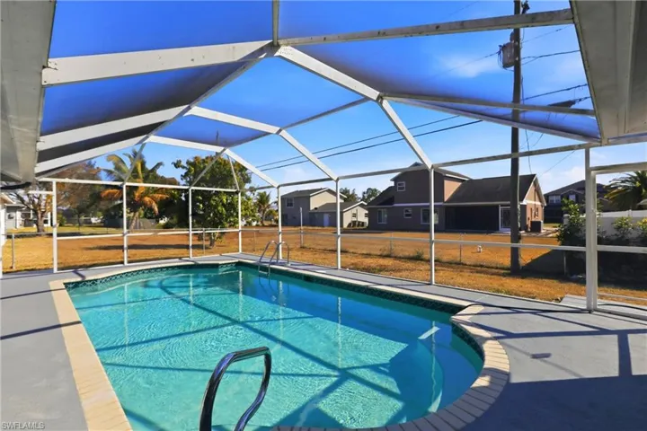 Outdoor pool featuring a sunroom, glass enclosure, a patio area, and a lawn