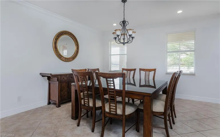 Tiled dining room featuring ornamental molding and a chandelier